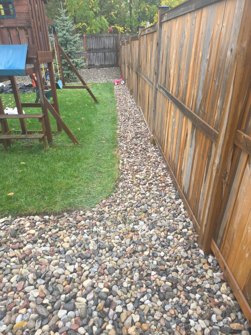 Small stone installation along fence in backyard